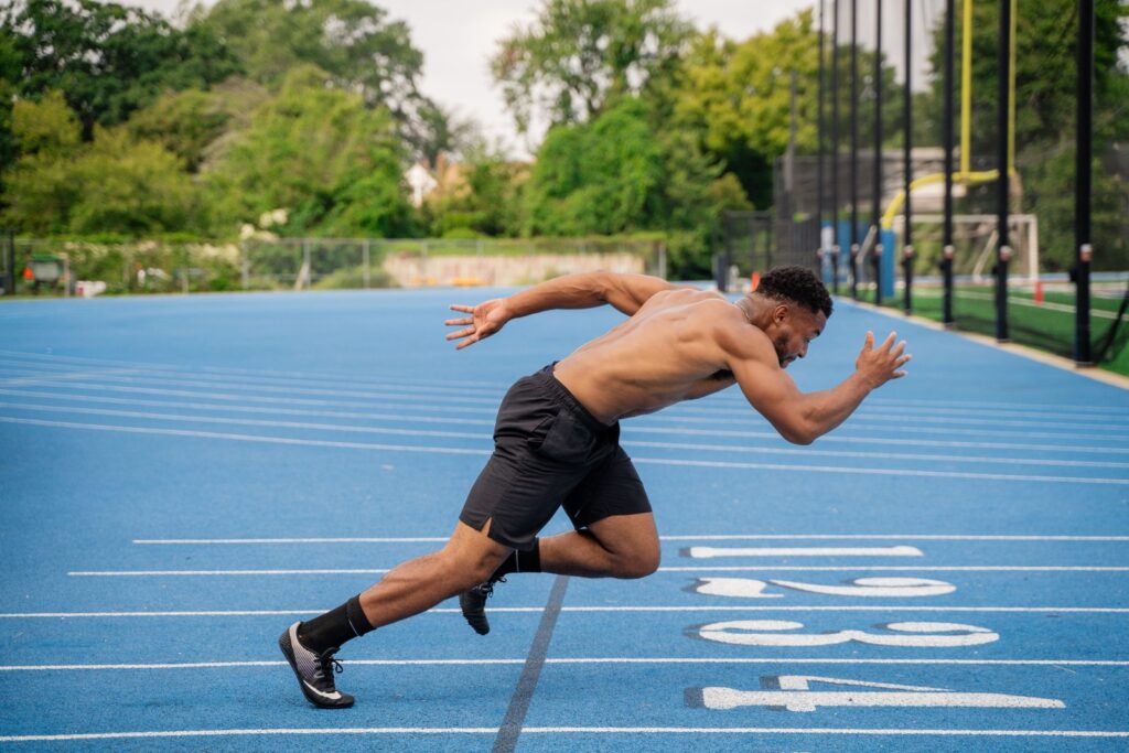 Male athlete sprinting on a blue outdoor running track